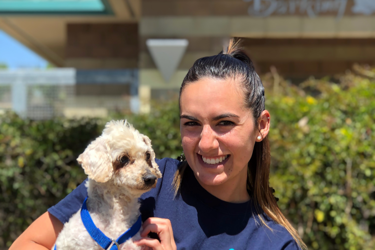 Female volunteer holding small white dog