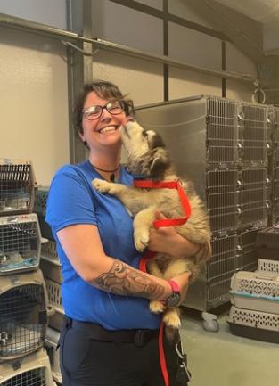 Animal Services Counselor Ashley poses with small dog that is part of a 60 dog rescue flight.