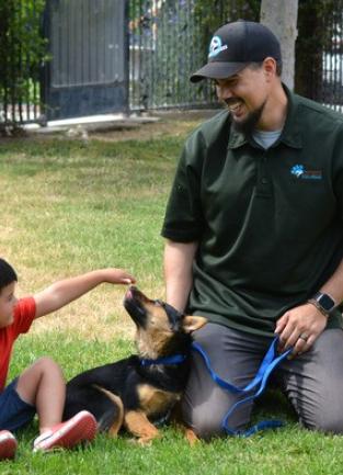 Riverside County Animal Services Staff playing with a puppy and small child